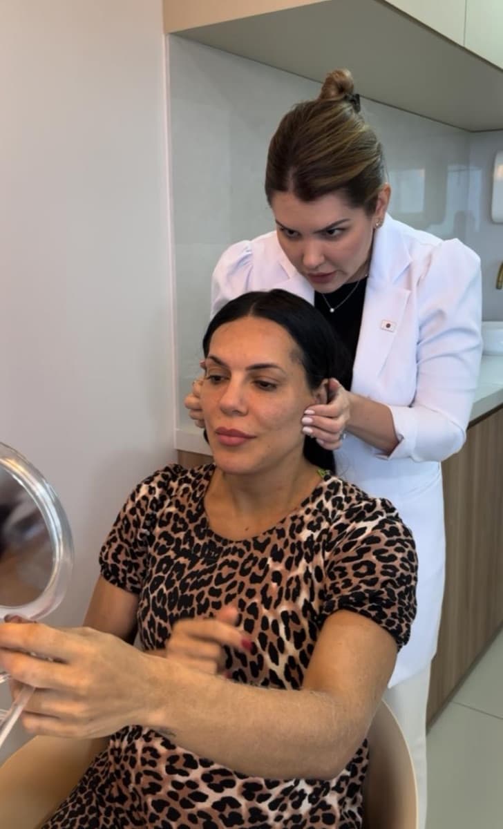 Dra. Natália Canto avaliando o rosto de uma paciente durante a consulta